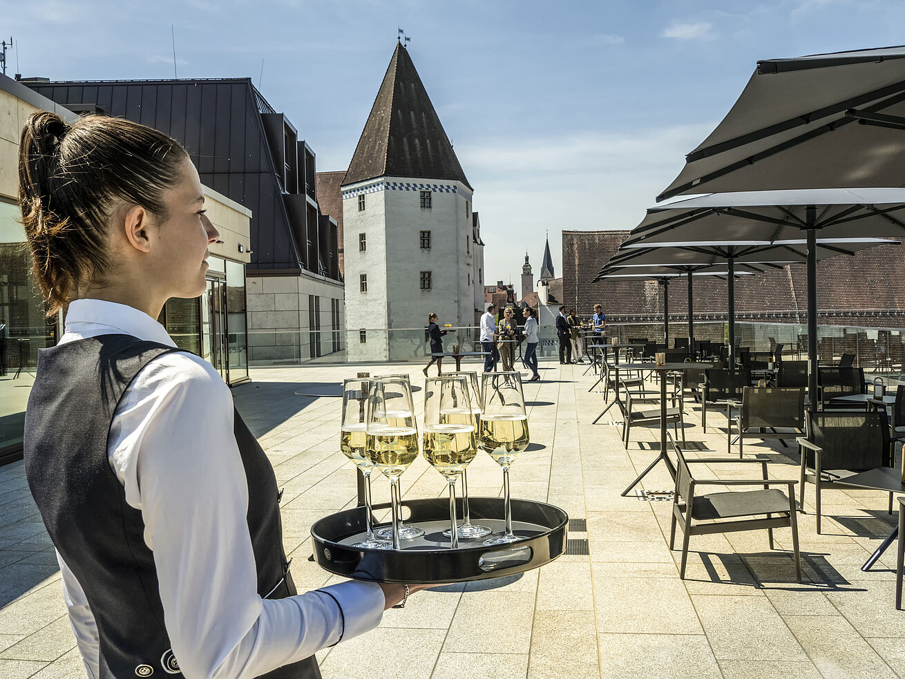Terrasse Kellnerin serviert Getränke auf der sonnigen Dachterrasse im Maritim Hotel Ingolstadt.