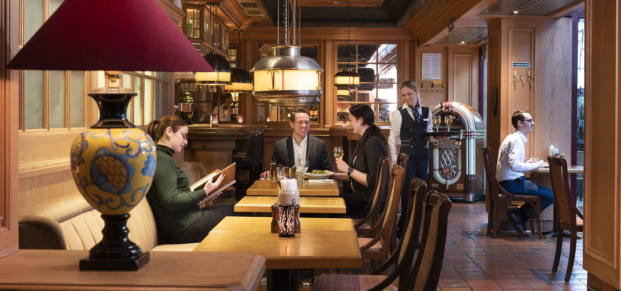Bier- und Weinstube "Kölsche Stuff" Gäste in der "Kölsche Stuff" genießen Essen und Getränke in gemütlicher Atmosphäre mit rustikalem Dekor.