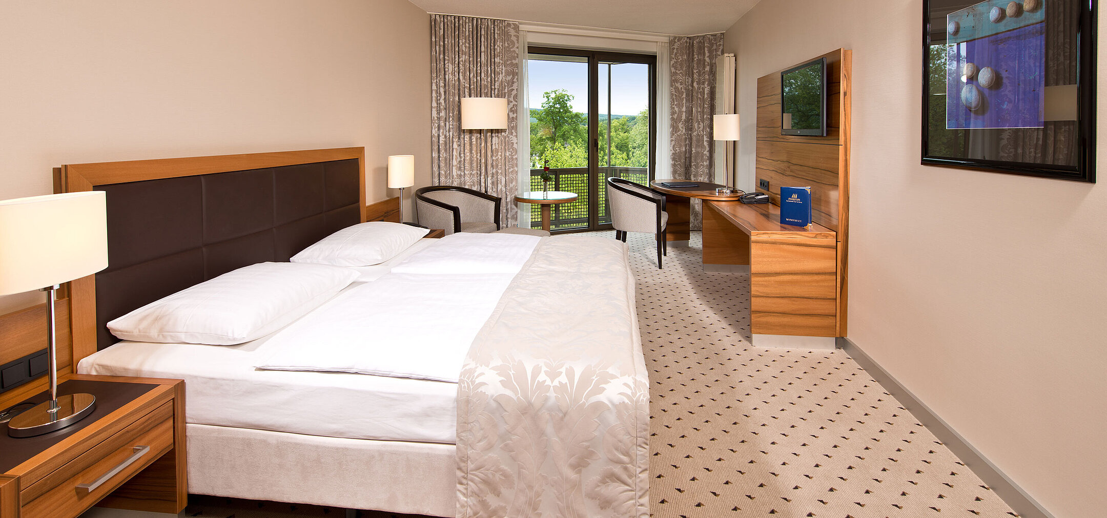 Comfort Zimmer Helles Zimmer im Maritim Hotel Bad Homburg mit gemütlichem Bett, Schreibtisch und Balkon mit grünem Ausblick.