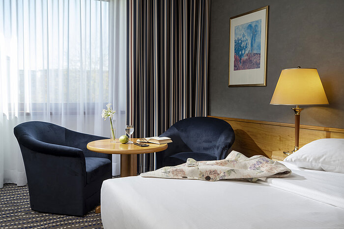 Classic Zimmer Sitzecke im Hotelzimmer mit Tisch, Buch, Glas Wasser und Apfel, perfekt zum Entspannen