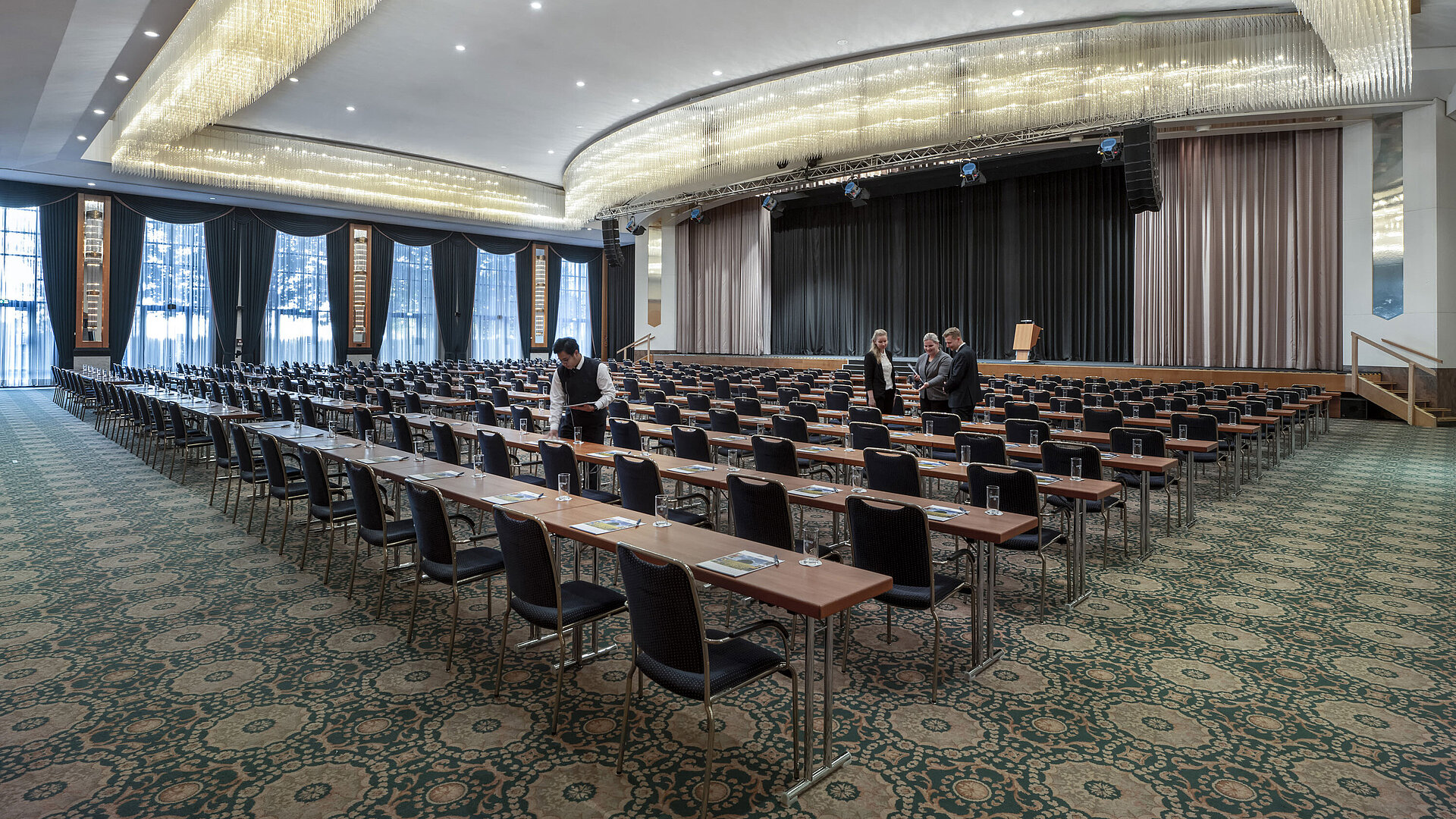 Saal Maritim Prächtiger Saal im Maritim Hotel Magdeburg mit Bühne, Reihenbestuhlung und luxuriösem Kronleuchter.