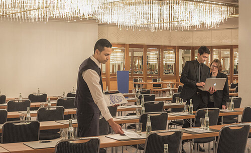 Maritim Tagungsservice Mitarbeiter bereitet Konferenzraum mit Kristallleuchtern im Maritim Hotel München vor