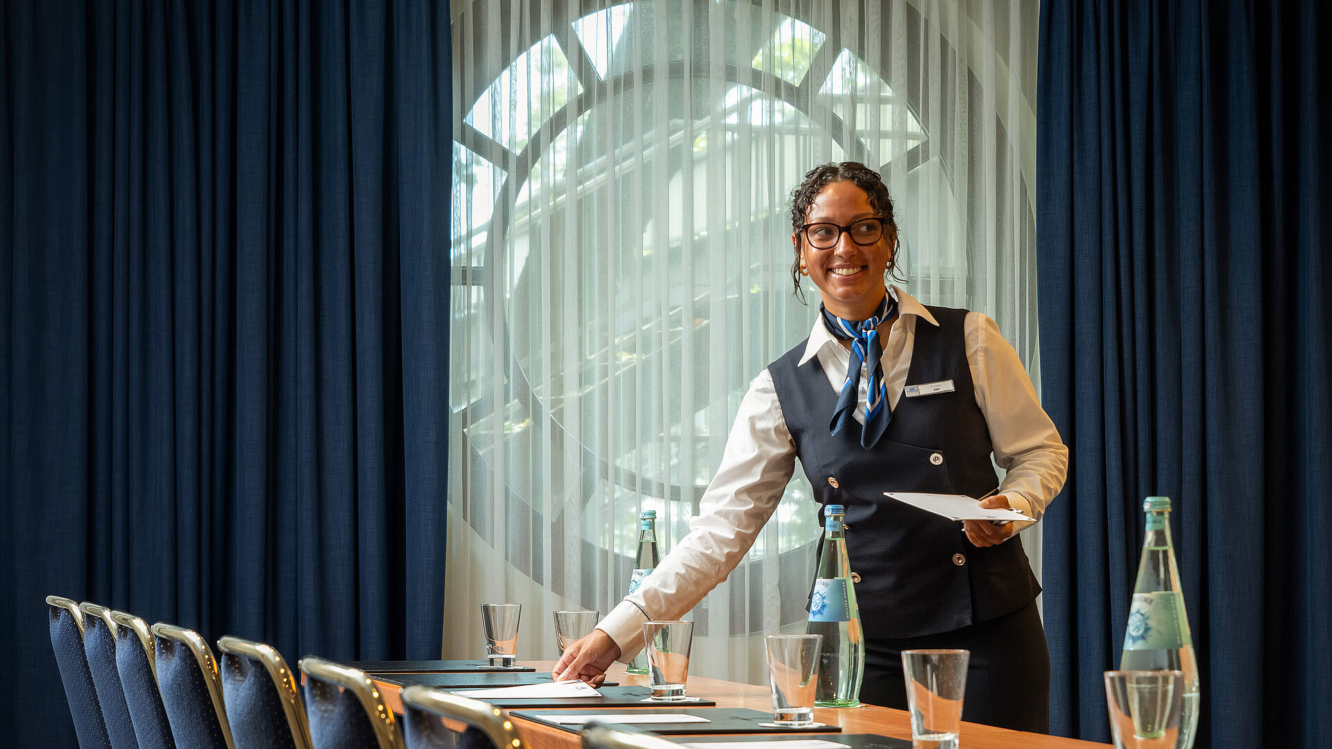 Tagungsservice Mitarbeiterin im Maritim Hotel Köln bereitet Konferenzraum mit Getränken und Unterlagen vor