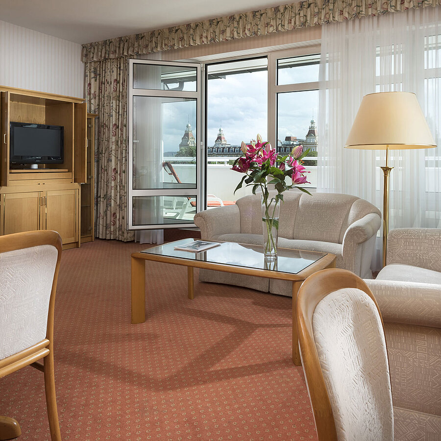 Junior Suite Großzügiger Wohnbereich mit Blumen, Sofa, Esstisch und Ausblick im Maritim Hotel Bad Wildungen