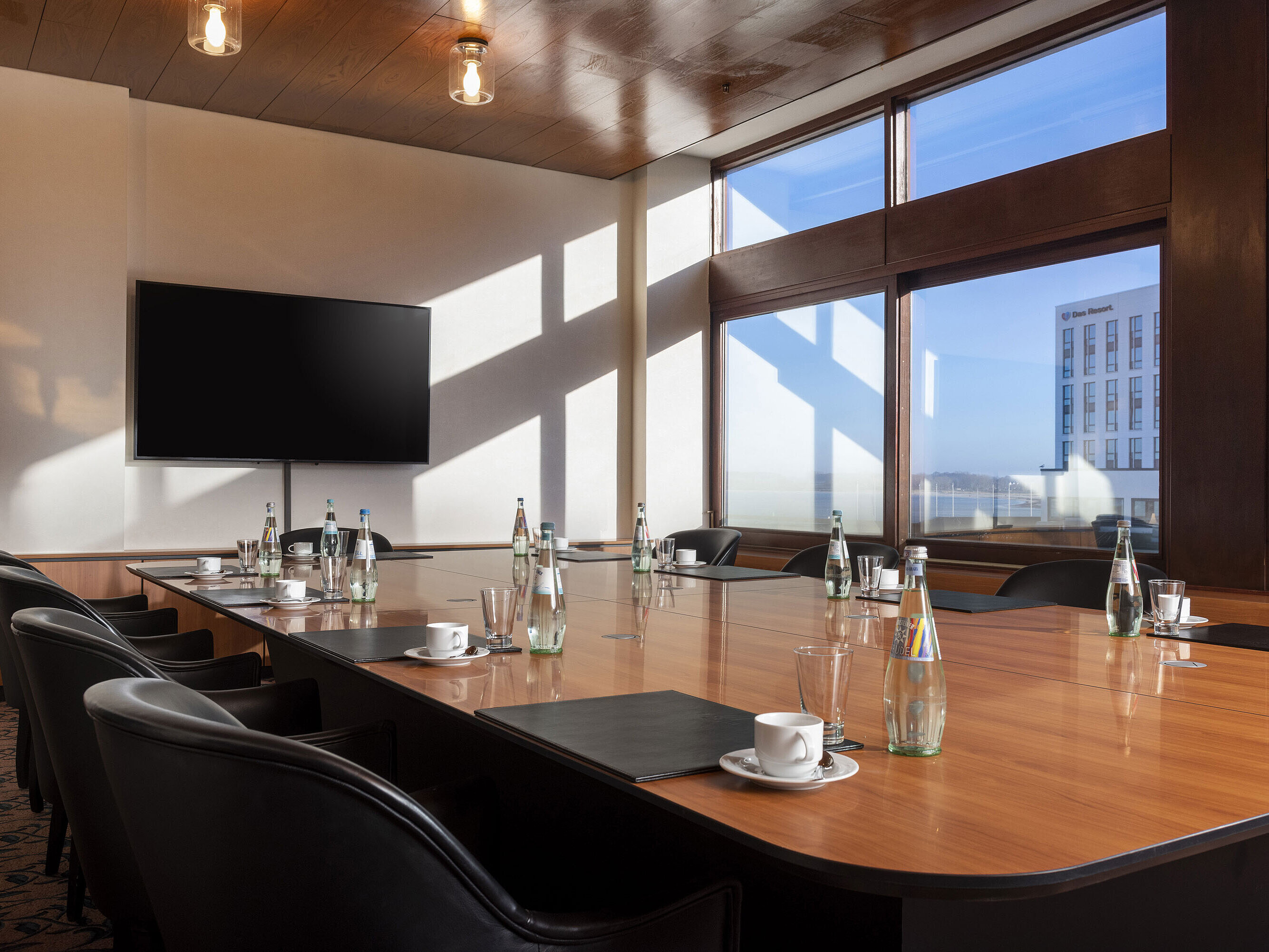 Salon Wuerzburg Heller Tagungsraum im Maritim Hotel Travemünde mit großem Bildschirm und Blick durch Panoramafenster