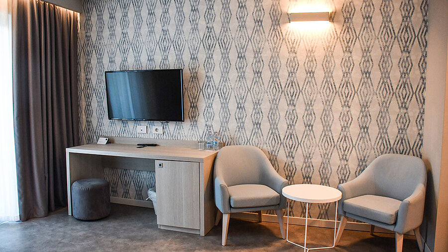 Standard Zimmer Moderner Sitzbereich mit Fernseher und Schreibtisch im Zimmer des Maritim Resort Calabria