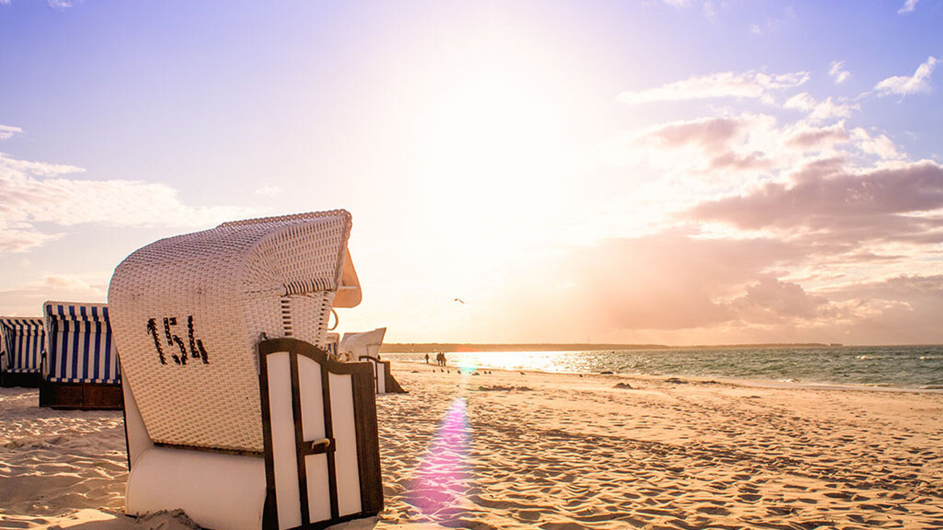 © Sina Ettmer - AdobeStock.com Strandkorb am Meer bei Sonnenuntergang mit warmem Licht und ruhiger Urlaubsatmosphäre