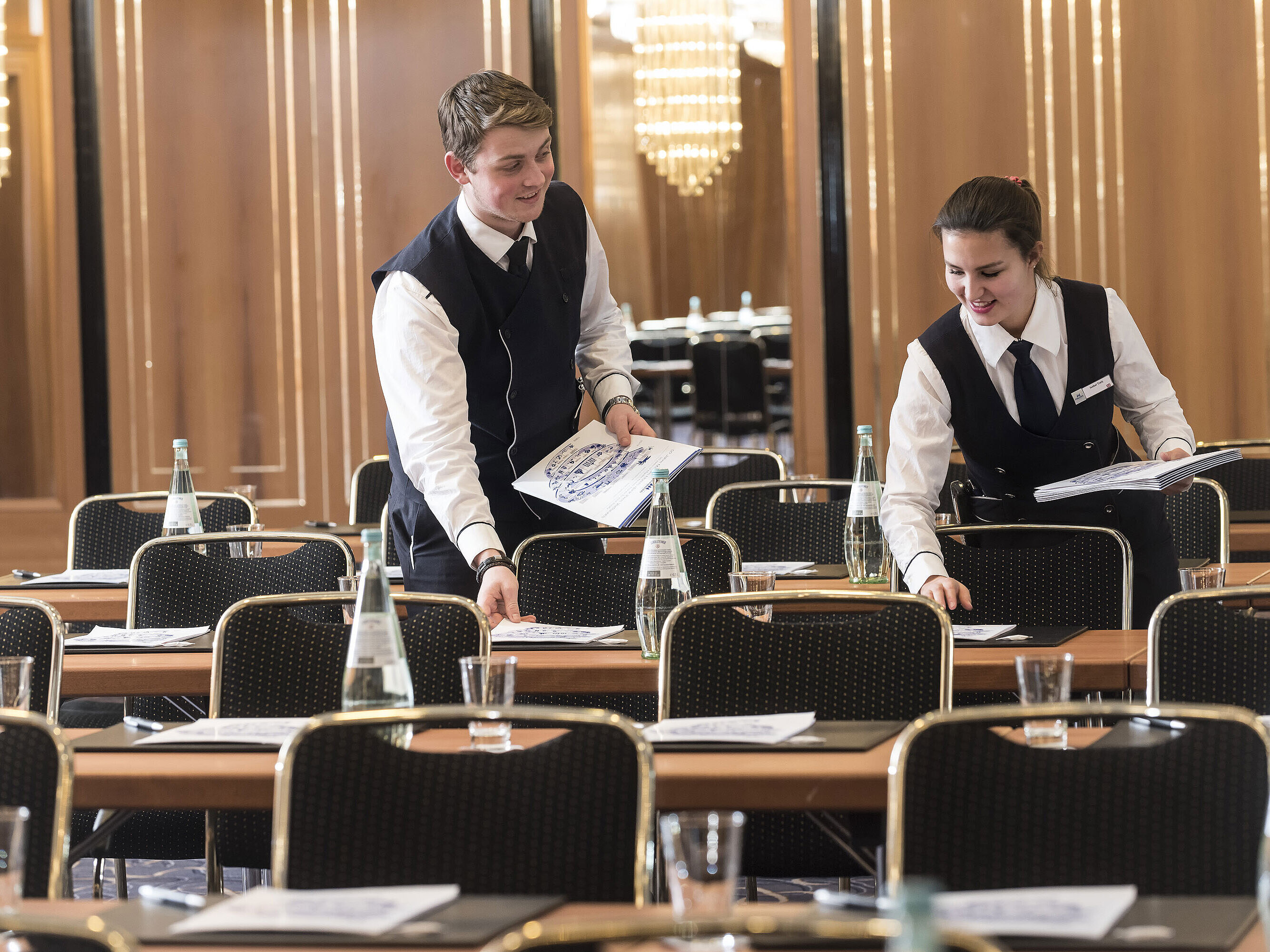 Tagungsservice Zwei Mitarbeitende legen Konferenzunterlagen auf die Tische im Maritim Hotel Stuttgart