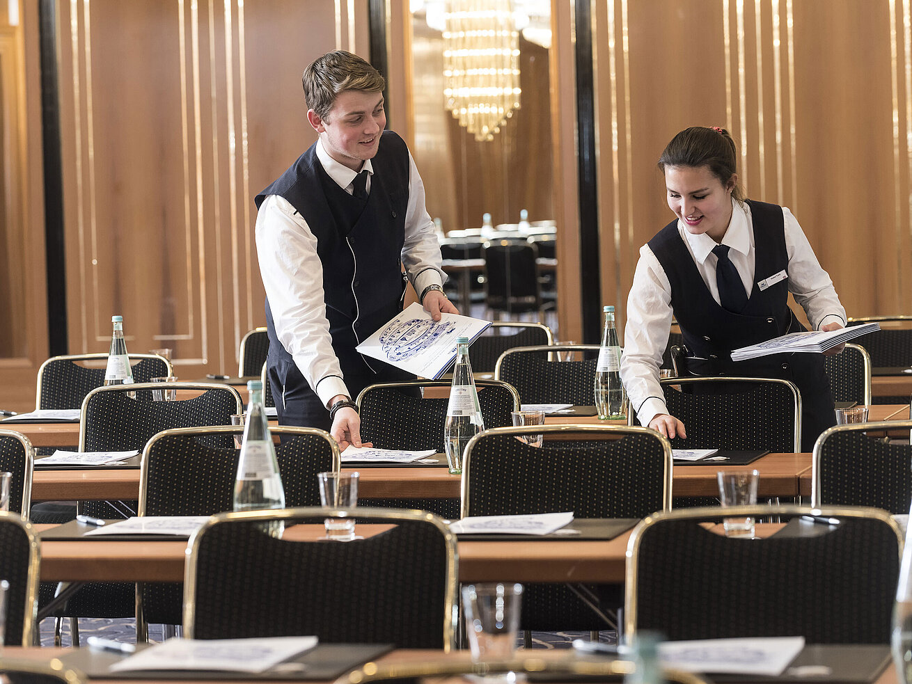 Tagungsservice Zwei Mitarbeitende legen Konferenzunterlagen auf die Tische im Maritim Hotel Stuttgart