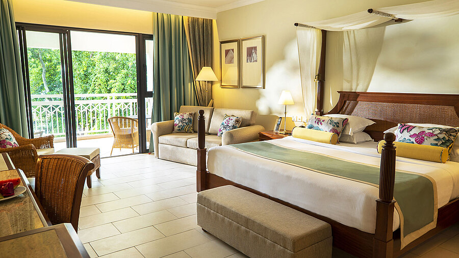 Deluxe plus Zimmer Großzügiges Hotelzimmer mit Himmelbett, Sofa, Balkon und Blick ins Grüne