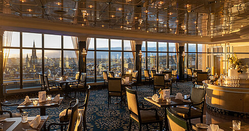 "Das Ulmer" Restaurant Restaurant im Maritim Hotel Ulm mit stilvollen Sitzplätzen, Panoramafenstern und Blick über Ulm bei Sonnenuntergang