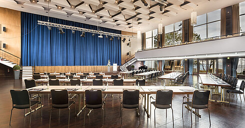 Saal Maritim Großer Saal „Maritim“ im Maritim Seehotel Timmendorfer Strand mit Bühne, blauen Vorhängen und Bestuhlung für Tagungen.