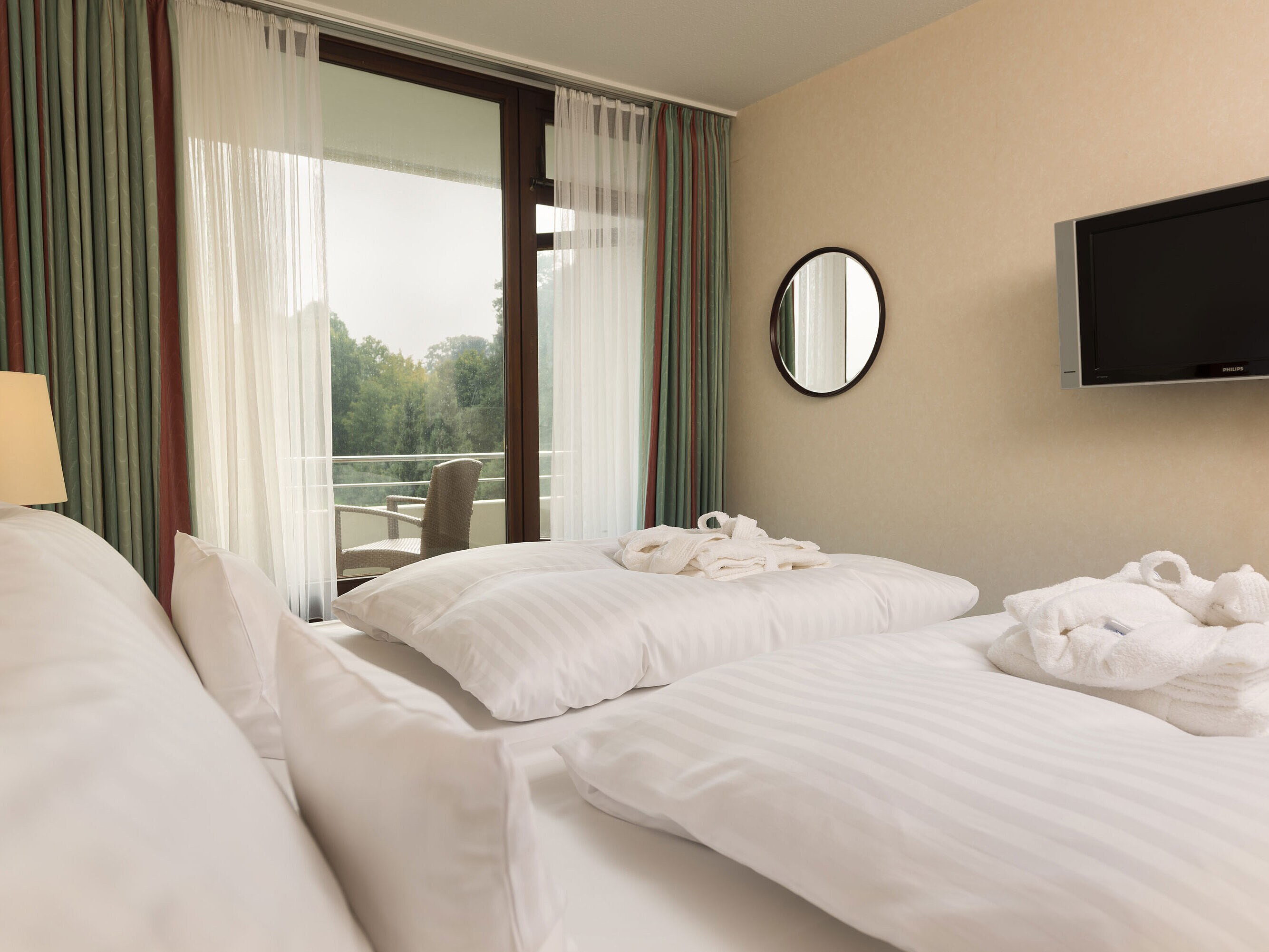 Junior Suite Doppelbett mit TV, Bademantel und Ausblick auf den Balkon im Maritim Hotel Bad Salzuflen