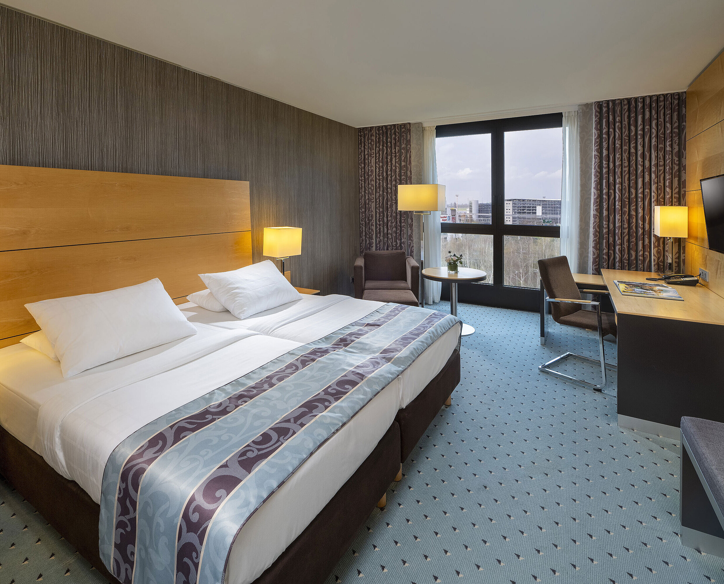 Comfort Zimmer Comfort Zimmer im Maritim Hotel Düsseldorf mit großem Doppelbett, Schreibtisch, Sessel und Panoramafenster.