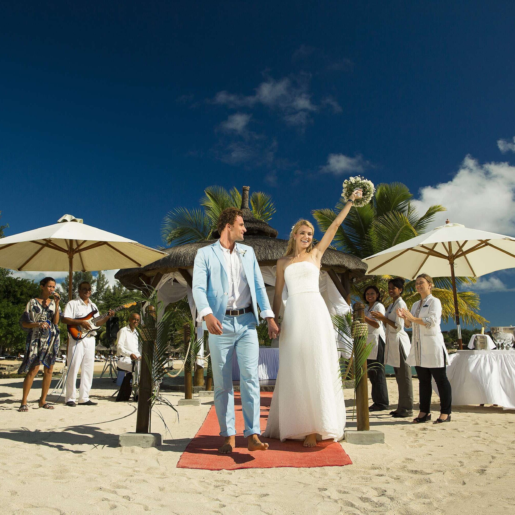 Heiraten am Strand Brautpaar feiert Strandhochzeit mit Gästen, Musik und Applaus unter Palmen am Meer