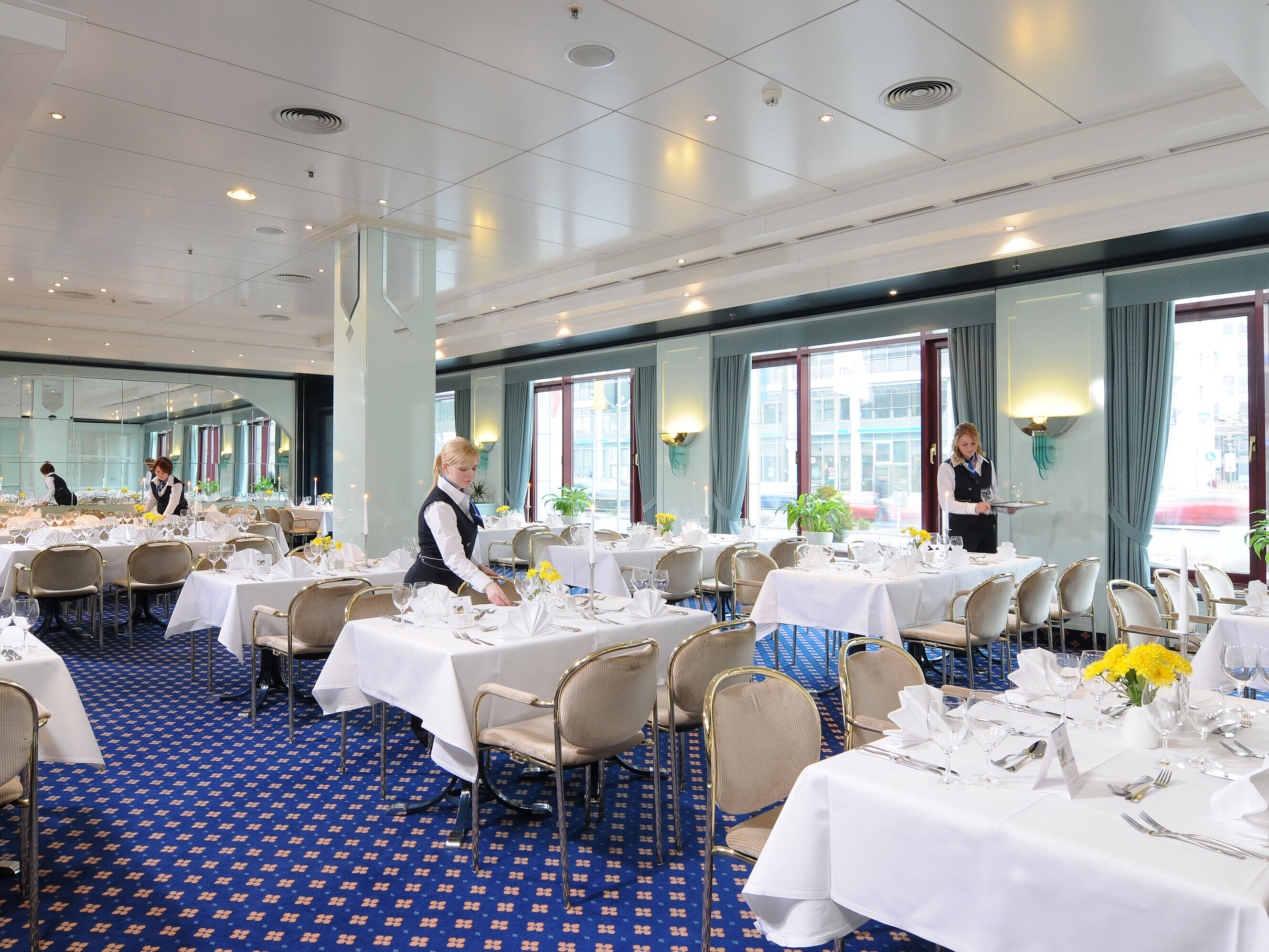 Salon Bonn Tagungsraum Salon Bonn im Maritim Hotel Magdeburg mit weiß gedeckten Tischen, eleganter Dekoration und freundlichem Servicepersonal.