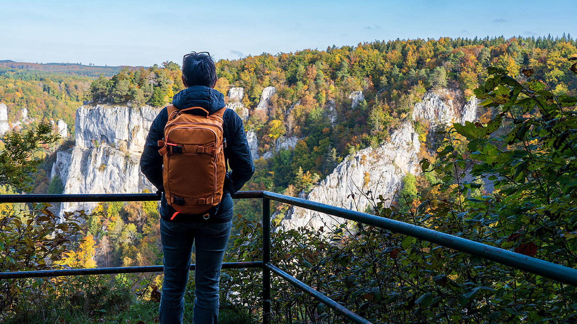 © Volker Loche - AdobeStock.com Wanderer mit Rucksack genießt den Ausblick auf die Felsenlandschaft im Donautal.