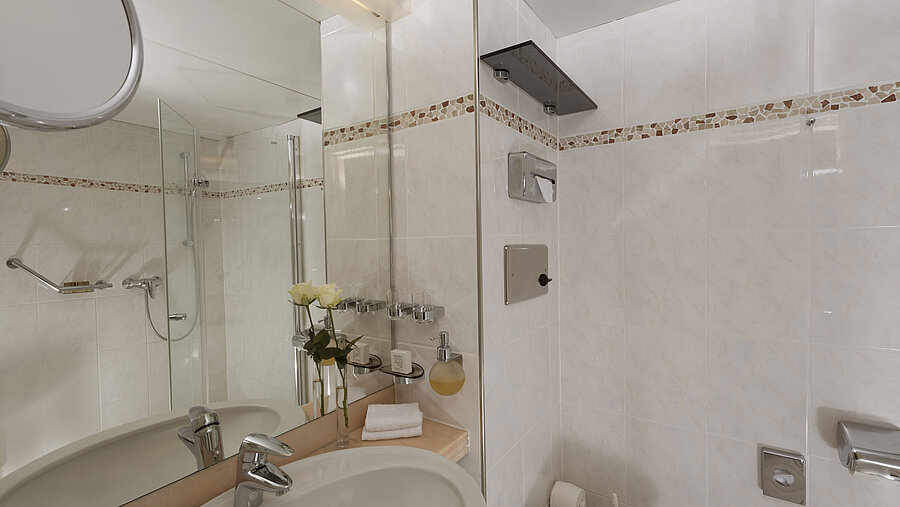 Badezimmer Helles Bad im Maritim Hotel Bad Salzuflen mit Dusche, großem Spiegel und weißen Fliesen