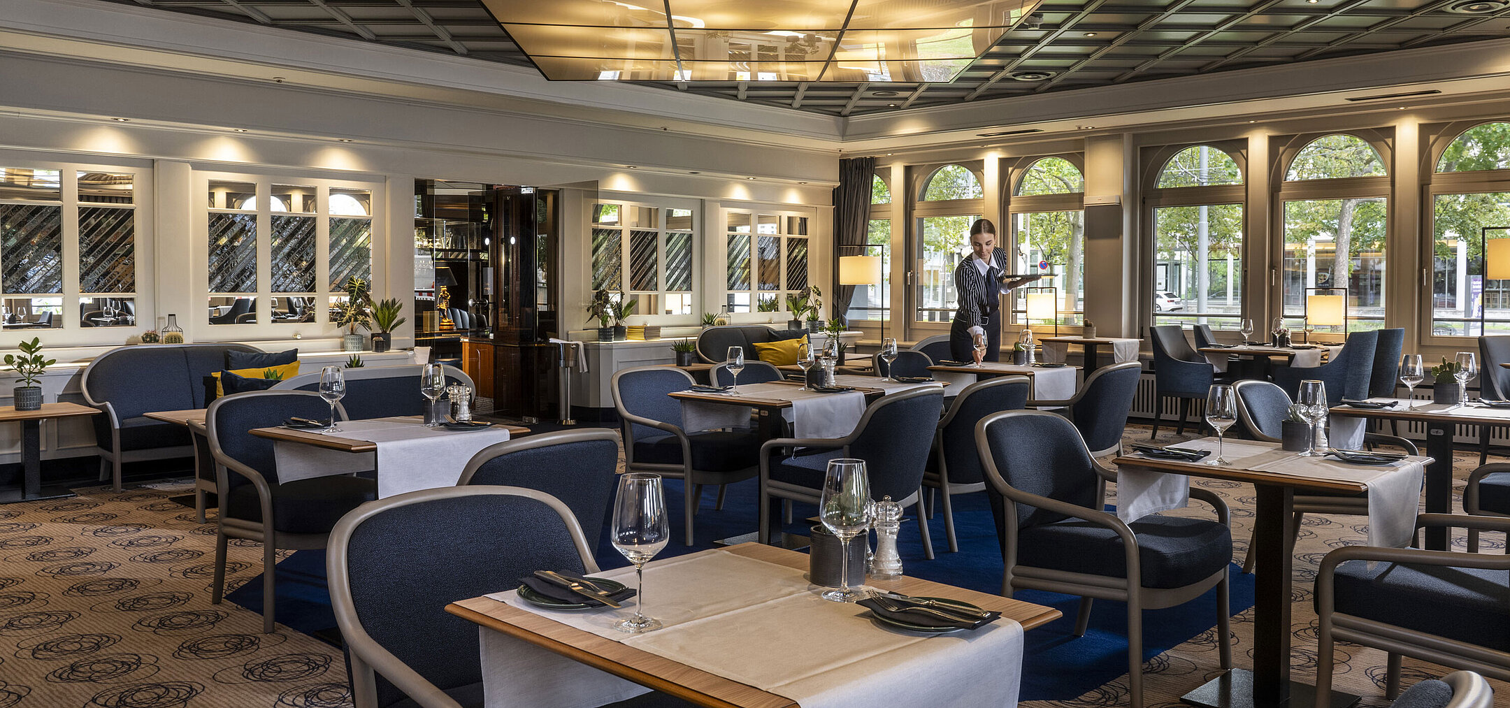 Lounge Restaurant Modernes Restaurant im Maritim Darmstadt mit gedeckten Tischen und elegantem Design. Eine Mitarbeiterin sorgt für den Service