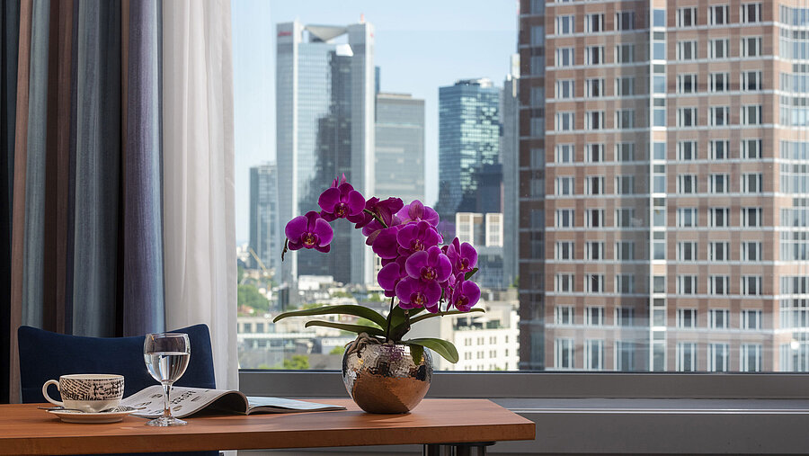 Superior Skyline Zimmer Ausblick aus dem Zimmer im Maritim Hotel Frankfurt mit Skyline-Panorama, Schreibtisch und eleganter Orchidee.