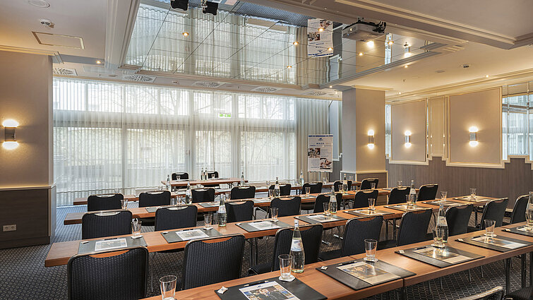 Saal München Tagungsraum mit Fensterfront, Tischen und Wasserflaschen im Maritim Hotel München