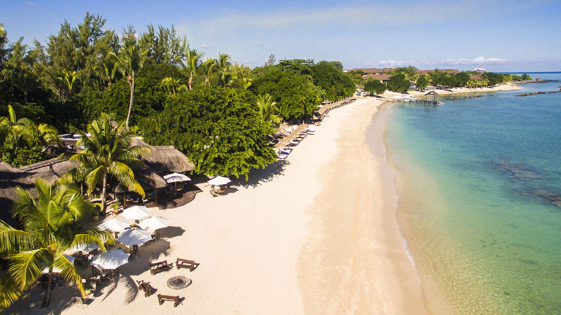 Strand Der weiße Sandstrand im Maritim Resort & Spa Mauritius lädt zum Entspannen unter Palmen und Sonnenschirmen ein