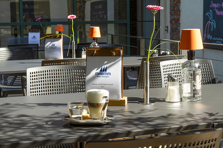 Terrasse Cappuccino, Wasser und Gebäck auf der sonnigen Terrasse des Maritim Hotel Stuttgart mit Menükarte