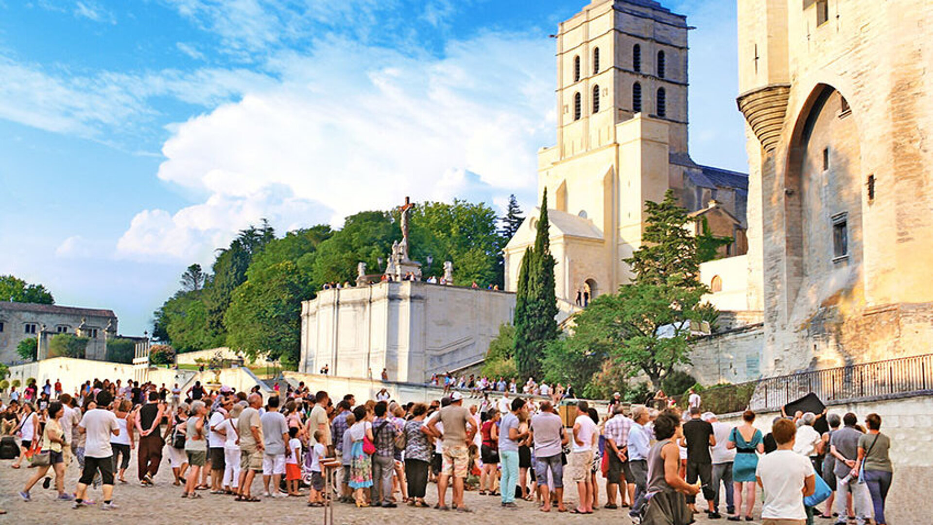 © lamax - AdobeStock.com Menschen versammeln sich vor dem historischen Palais des Papes und der Kathedrale beim Festival d'Avignon.