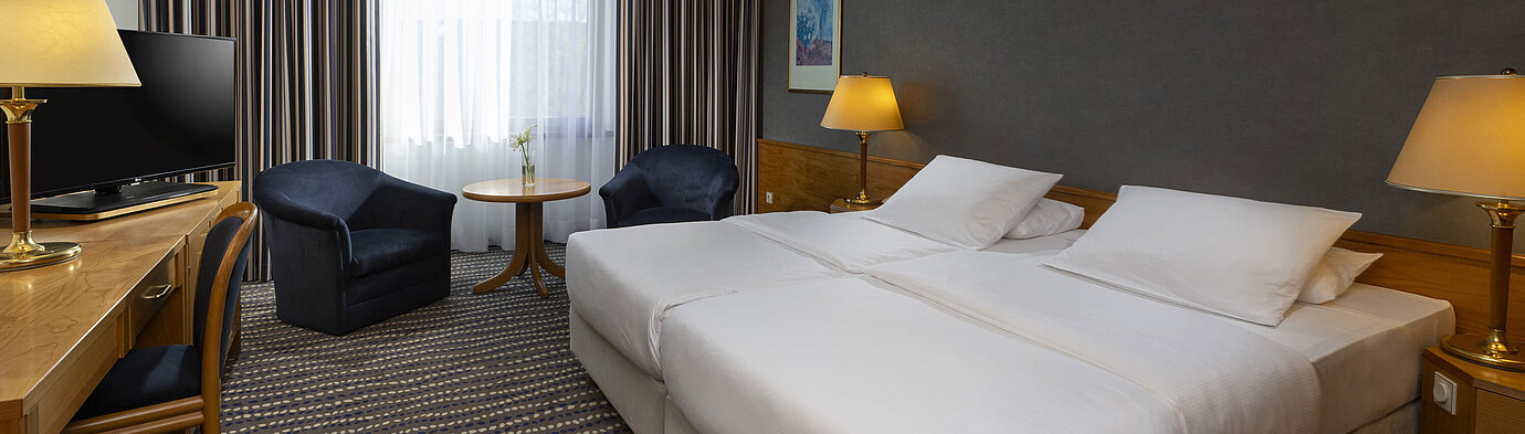 Classic Zimmer Hotelzimmer mit Doppelbett, TV, Schreibtisch und gemütlicher Sitzecke, ideal für Erholung und Komfort