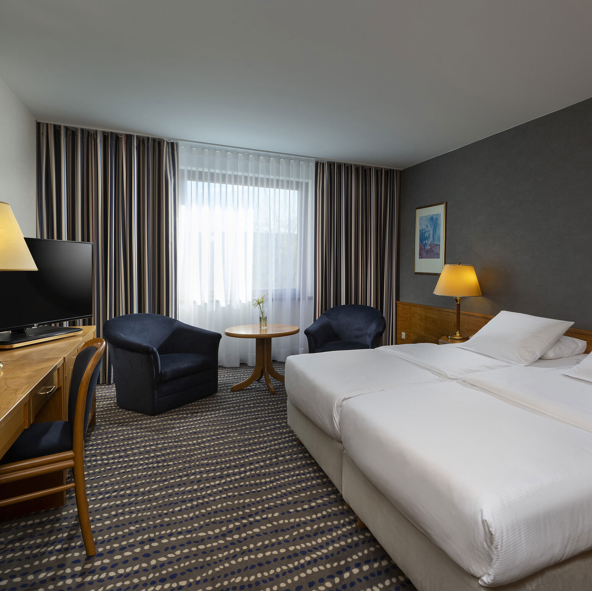 Classic Zimmer Hotelzimmer mit Doppelbett, TV, Schreibtisch und gemütlicher Sitzecke, ideal für Erholung und Komfort