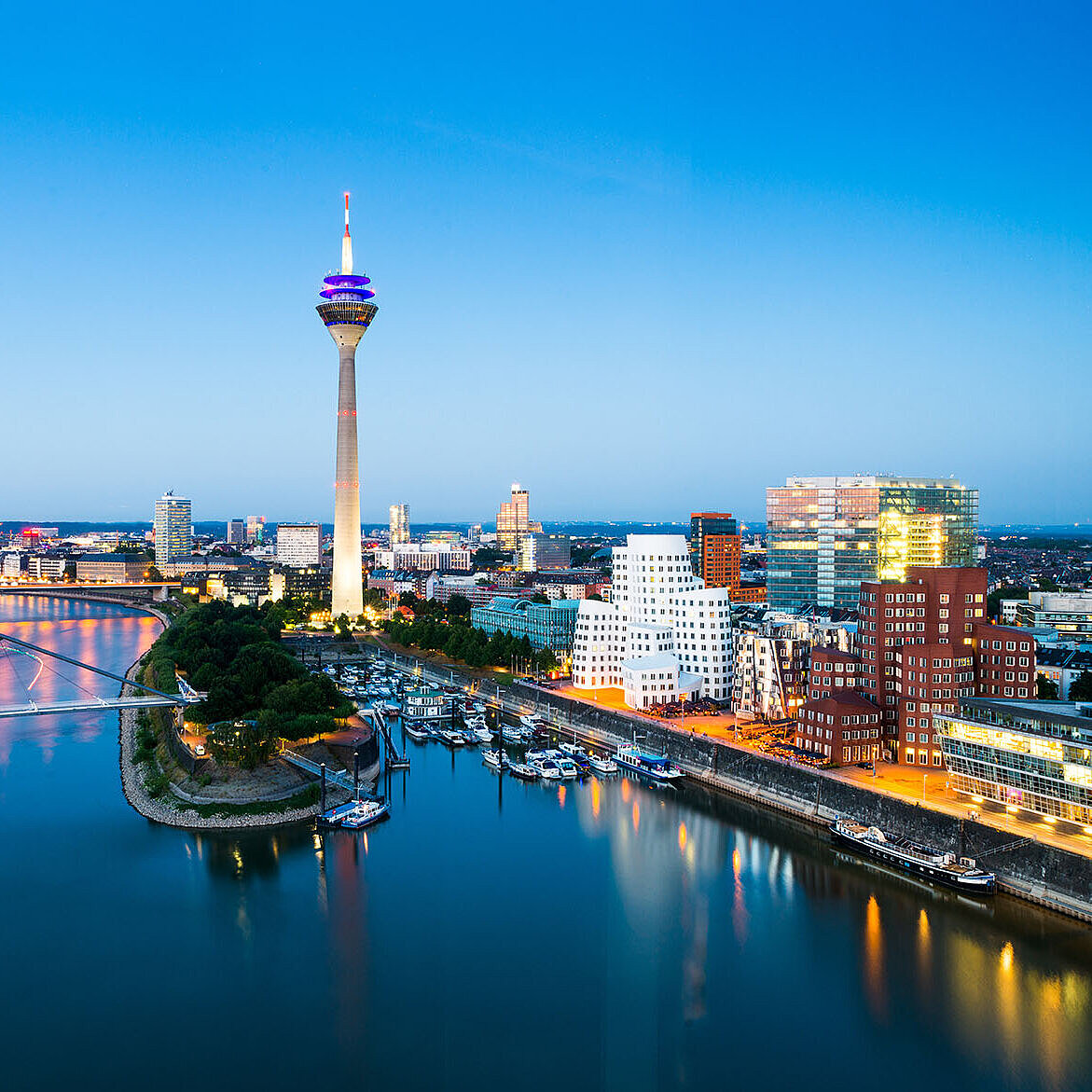 © conorcrowe - AdobeStock.com Düsseldorf Skyline mit Rheinturm, Rheinpromenade und moderner Architektur bei Abenddämmerung.