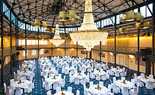 Alte Stuttgarter Reithalle Großer Bankettsaal mit runden, festlich gedeckten Tischen und beeindruckenden Kronleuchtern im Maritim Hotel Stuttgart