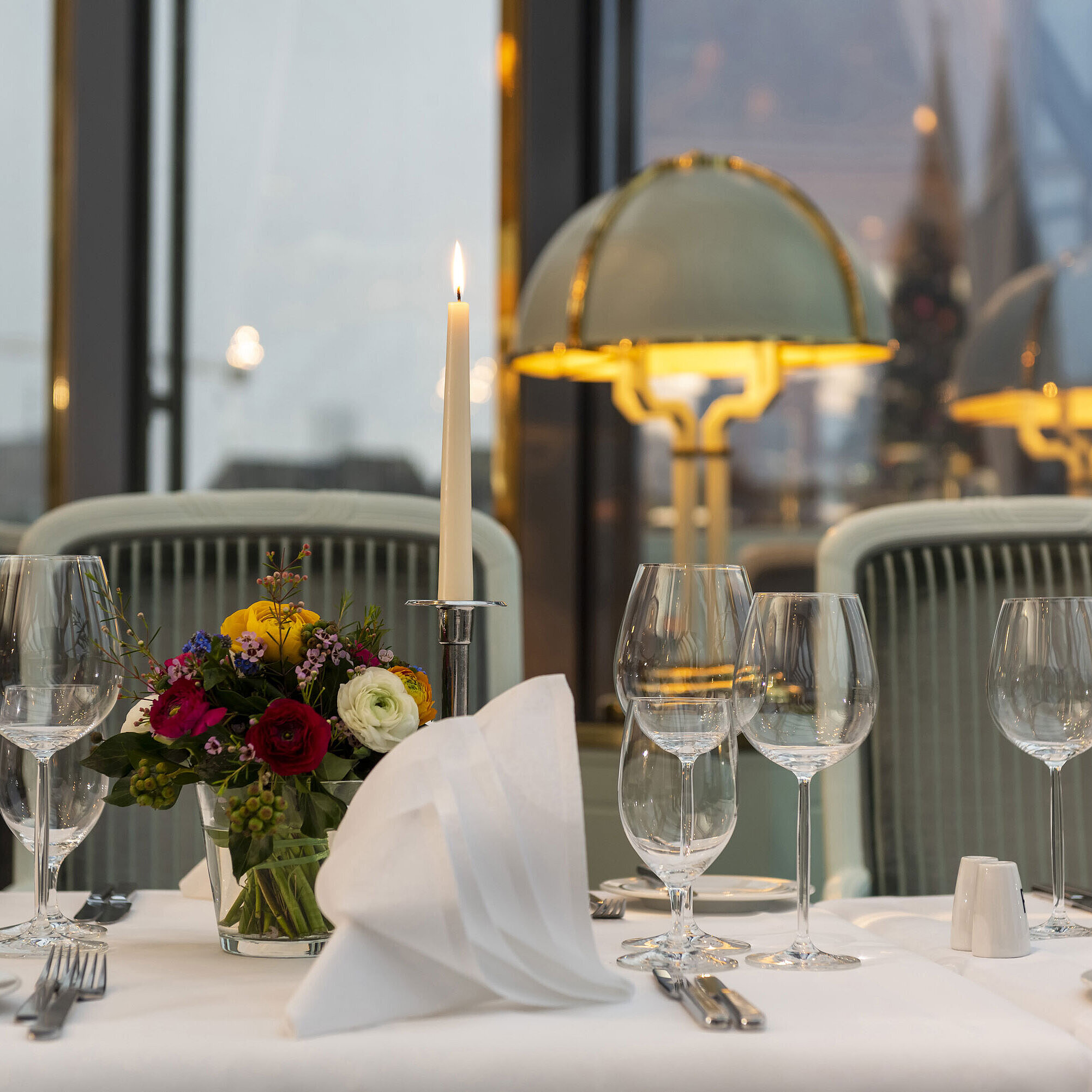 Restaurant "Bellevue" Elegant gedeckter Tisch im Restaurant mit Kerze, Weingläsern und Blumenarrangement, perfekt für ein gehobenes Abendessen.