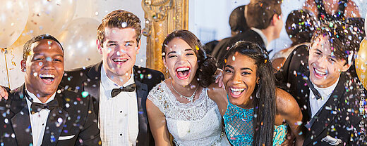 © kali9 - iStockphoto.com Gruppe junger Menschen in Abendkleidung feiert fröhlich mit Konfetti
