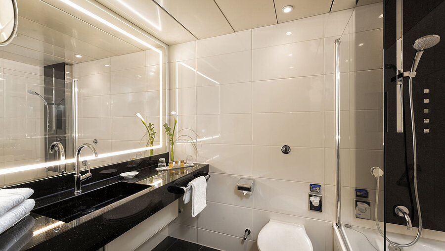 Badezimmer Modernes Badezimmer mit Dusche und Badewanne im Maritim Hotel Bonn, ausgestattet mit eleganten Armaturen und Spiegelbeleuchtung.