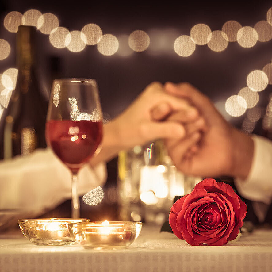© kieferpix - AdobeStock.com Romantisches Candle-Light-Dinner mit Rotwein, Rosen und Kerzenschein