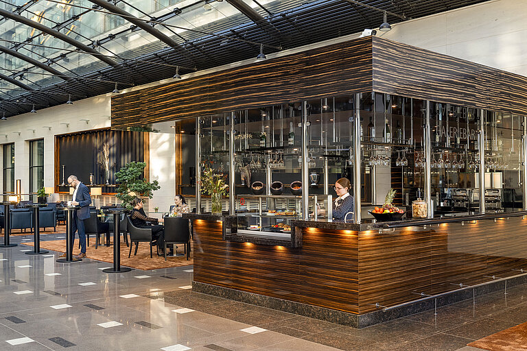 Galerie Bar Moderne Bar im Maritim Hotel Düsseldorf mit eleganter Ausstattung, Sitzbereichen und einer Mitarbeiterin hinter der Theke.