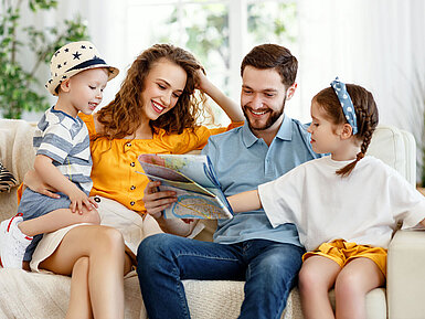 © JenkoAtaman - AdobeStock.com Glückliche Familie plant gemeinsam Urlaub zu Hause