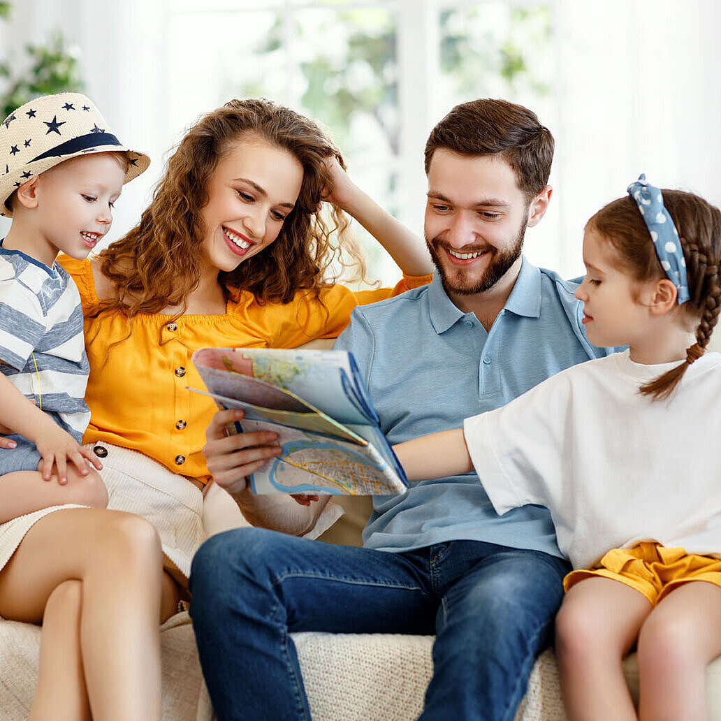 © JenkoAtaman - AdobeStock.com Glückliche Familie plant gemeinsam Urlaub zu Hause