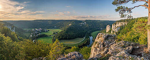 © mindscapephotos - AdobeStock.com Panorama über das Donautal mit Fluss, grünen Wiesen und steilen Felsen