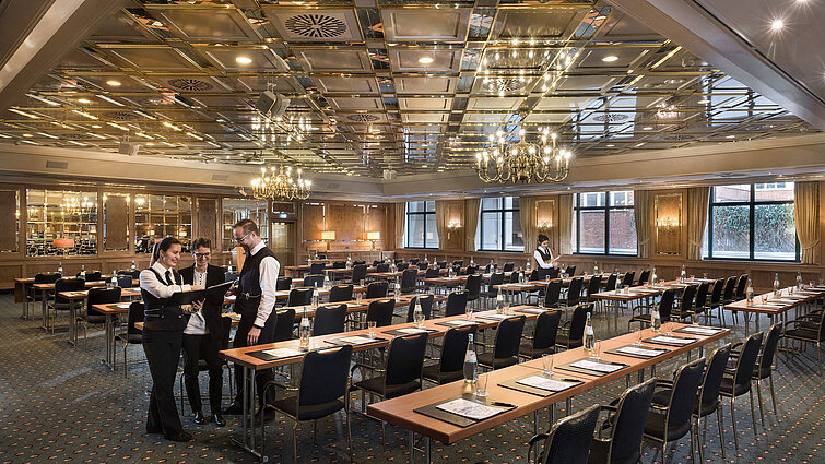 Saal Maritim Zwei Mitarbeitende bereiten einen Konferenzraum mit Reihenbestuhlung im Maritim Hotel Stuttgart vor