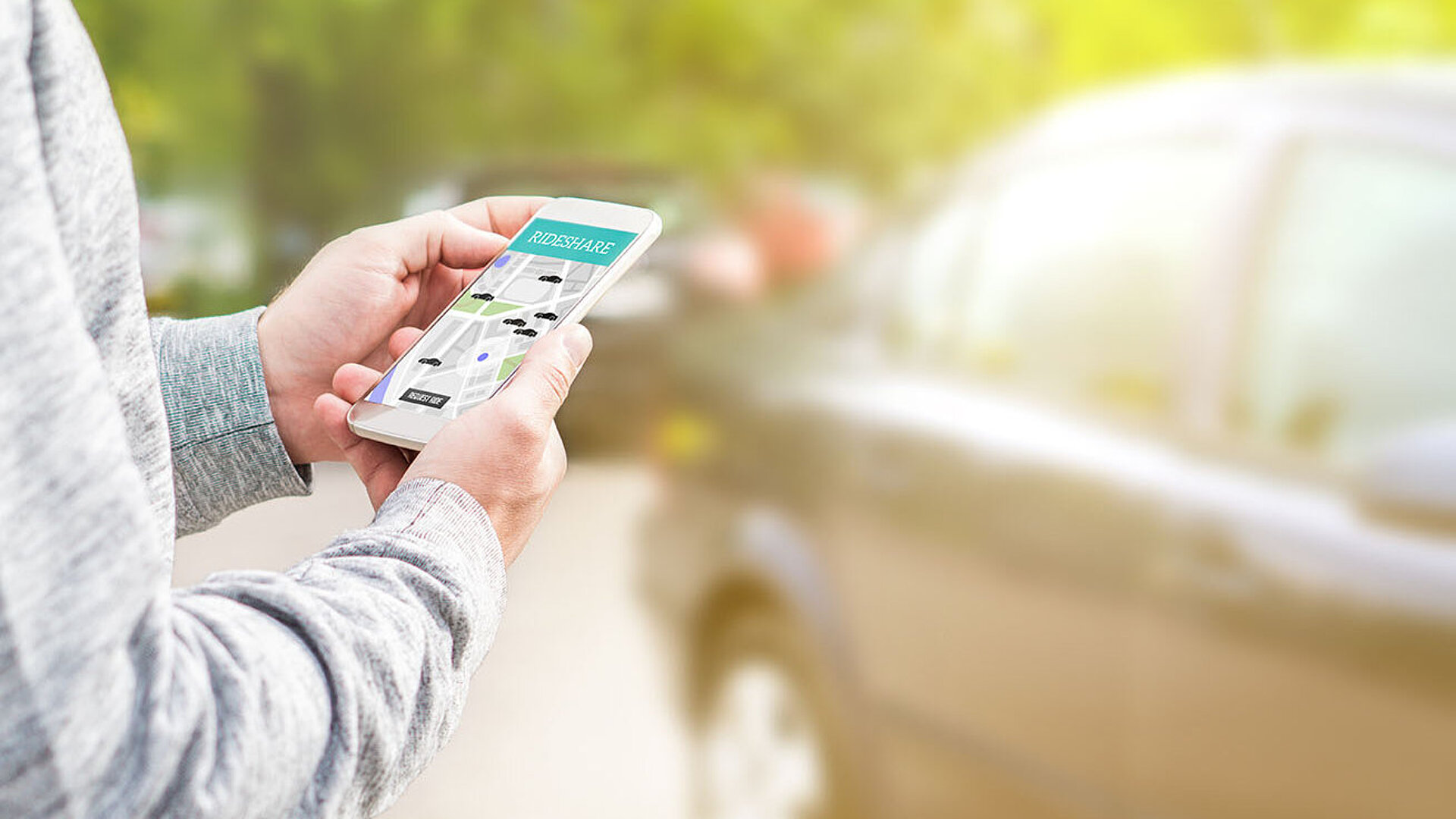 © terovesalainen-AdobeStock.com Person hält Smartphone mit Rideshare-App zur Buchung einer Mitfahrgelegenheit
