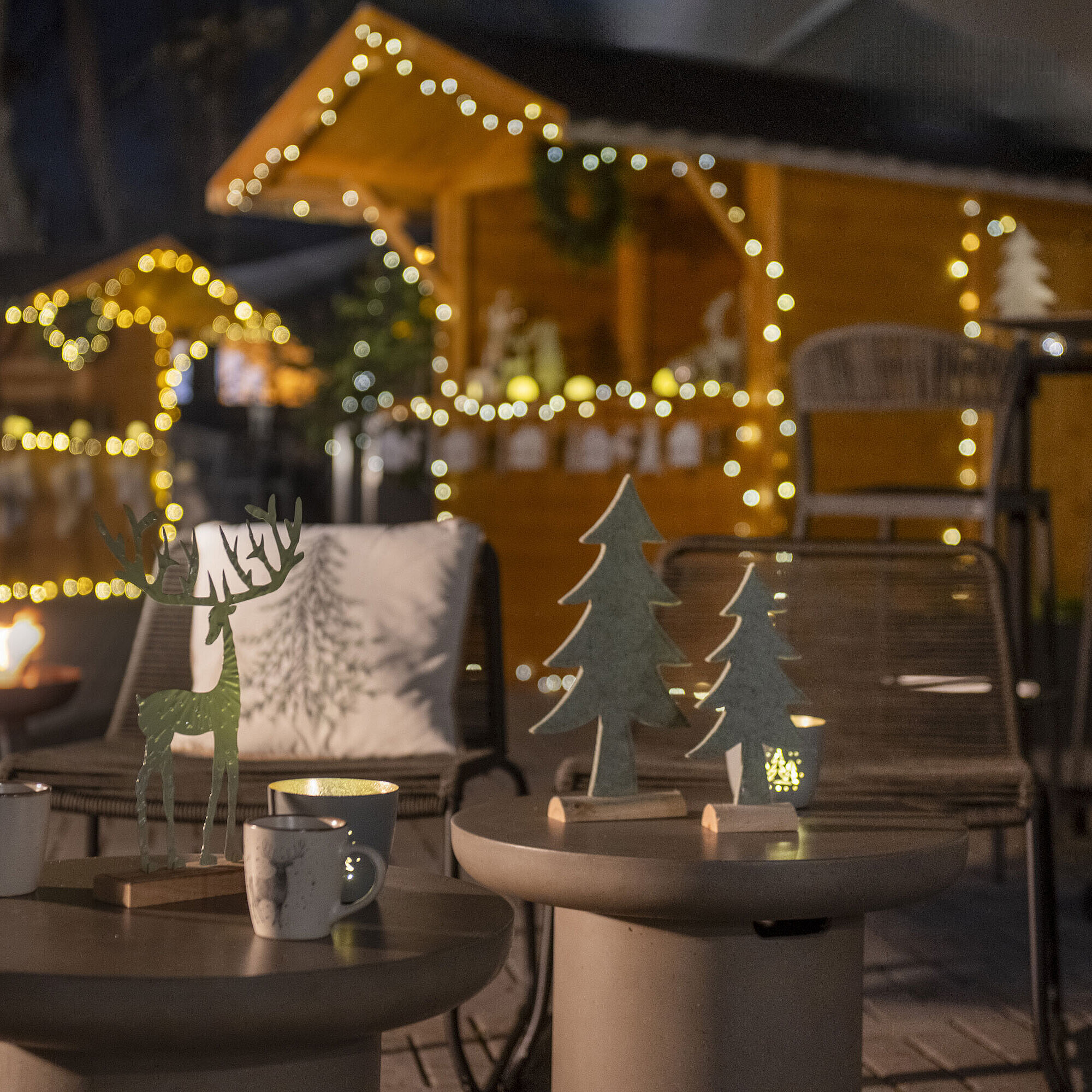 Maritim Weihnachtsdorf Weihnachtlich geschmückter Außenbereich des Maritim Hotels Darmstadt mit Lichterketten, Holzdekorationen und einem Feuerkorb.