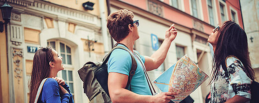 © Nejron Photo - AdobeStock.com Freunde erkunden mit Stadtplan eine historische Altstadt während eines Städtetrips