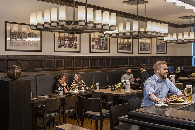 Rheinische Stov Gäste genießen Speisen im gemütlichen Restaurant "Rheinische Stov" des Maritim Hotel Düsseldorf mit stilvollem Interieur.