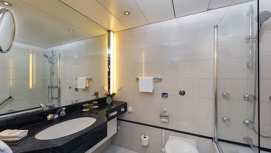 Badezimmer Modernes Badezimmer im Maritim Hotel Frankfurt mit großer Spiegelwand, stilvollem Waschbecken und Dusch-Badewanne.