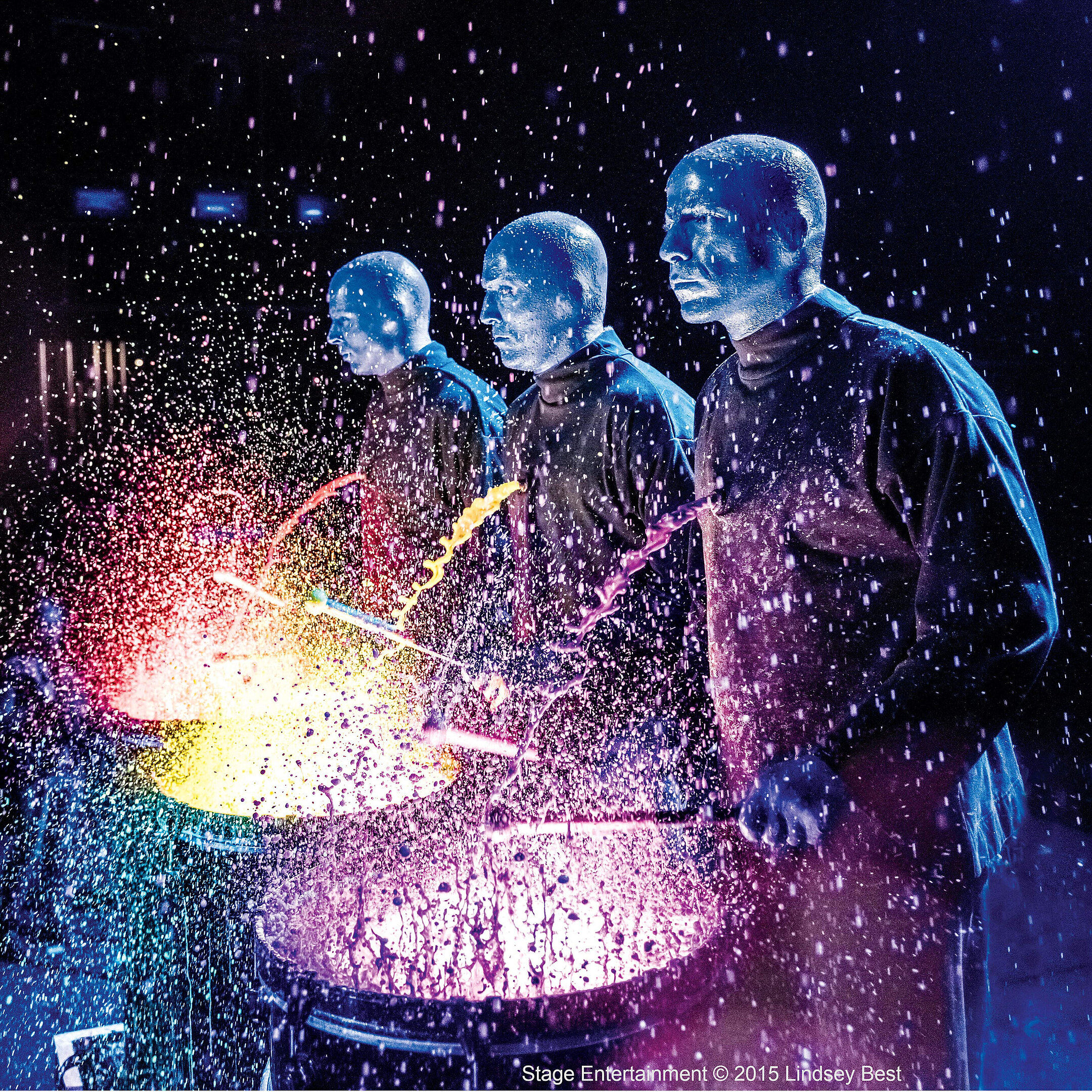 Blue Man Group Percussion-Show mit blau geschminkten Künstlern, leuchtenden Farben und Wassereffekten auf der Bühne