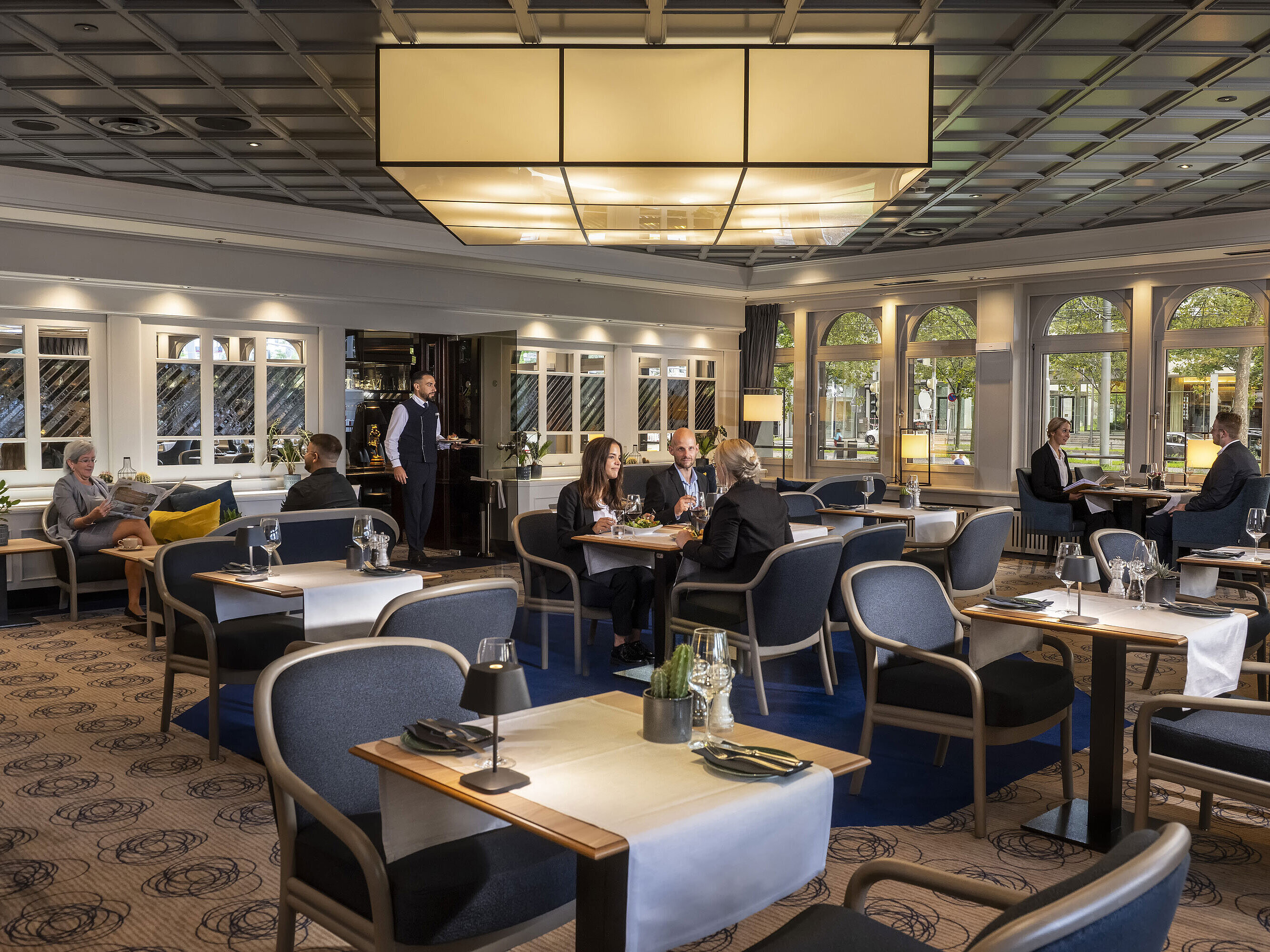 Lounge Restaurant Elegantes Restaurant mit Gästen, die speisen und entspannen. Moderne Einrichtung und große Fenster mit Ausblick.
