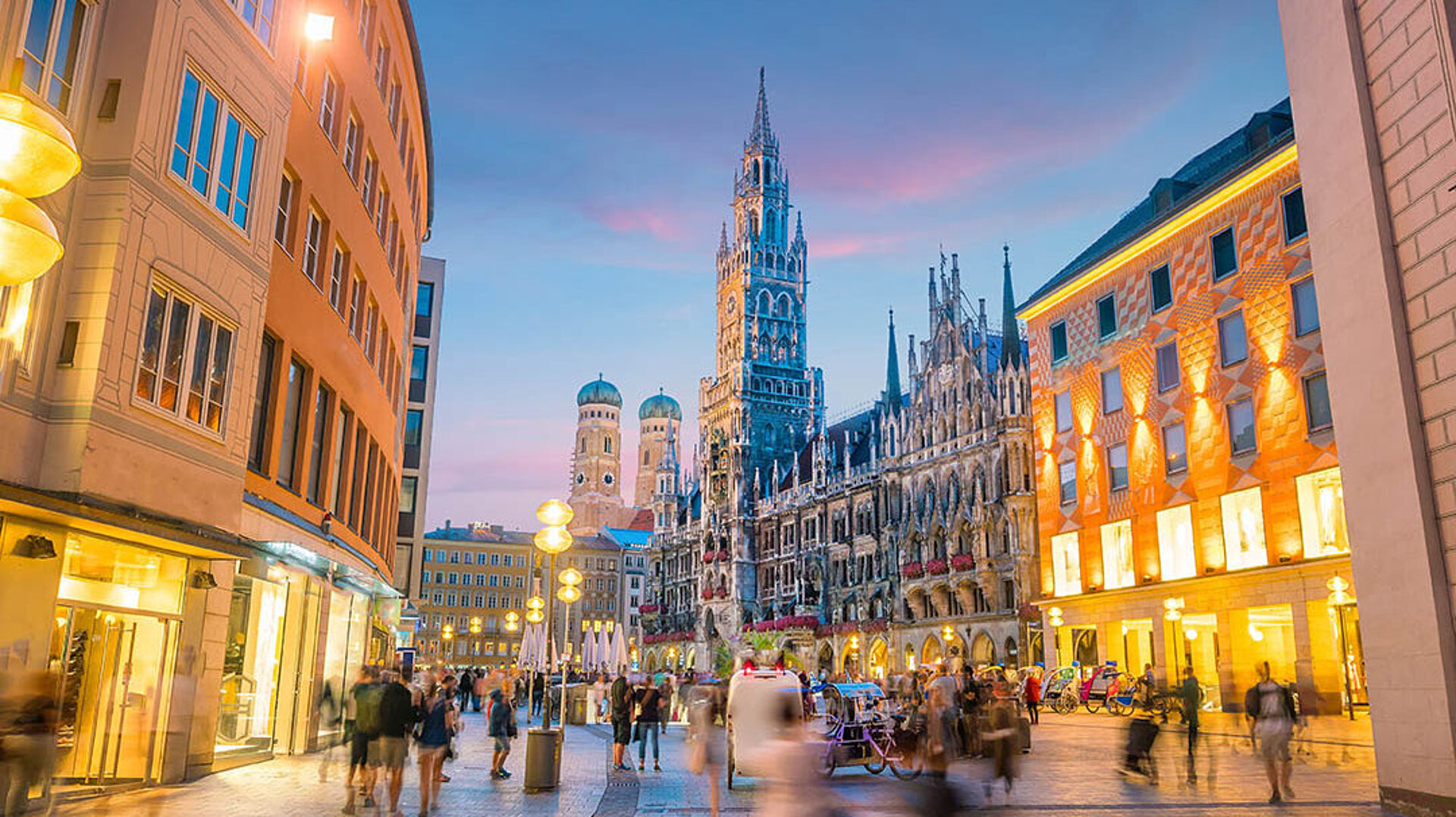 © f11photo - AdobeStock.com Marienplatz in München mit Neuem Rathaus, beleuchteten Gebäuden und lebendiger Innenstadt am Abend