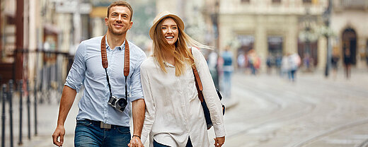© puhhha - AdobeStock.com Glückliches Paar spaziert Hand in Hand durch eine historische Altstadt